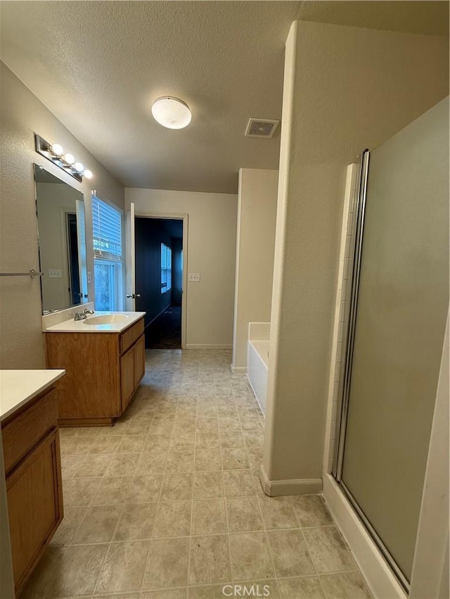 bathroom featuring vanity, separate shower and tub, and a textured ceiling