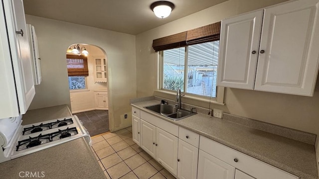 kitchen with sink, light tile patterned floors, white gas range oven, and white cabinets