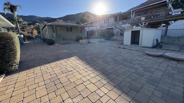 back of house featuring a balcony, a patio, a mountain view, and a storage unit