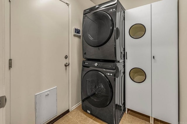 clothes washing area with laundry area, stacked washer / dryer, and light tile patterned flooring