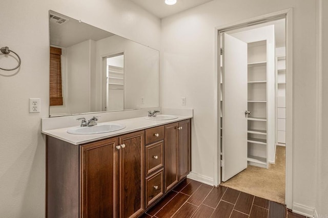 bathroom featuring double vanity, wood finish floors, a sink, and visible vents