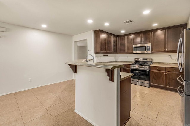 kitchen with a peninsula, appliances with stainless steel finishes, visible vents, and dark brown cabinets