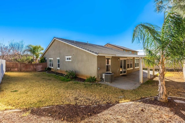 rear view of property featuring a lawn, a fenced backyard, cooling unit, a patio area, and stucco siding