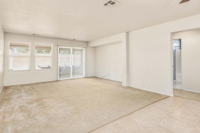 empty room with light carpet, baseboards, visible vents, and a ceiling fan