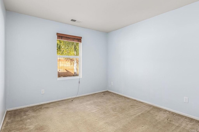 carpeted spare room with visible vents and baseboards