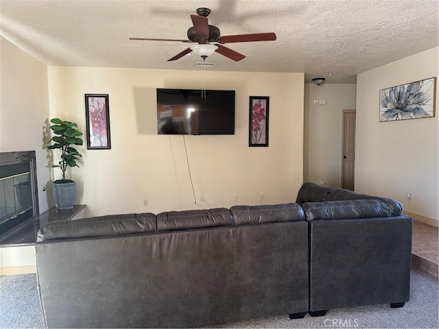 carpeted living room featuring ceiling fan and a textured ceiling