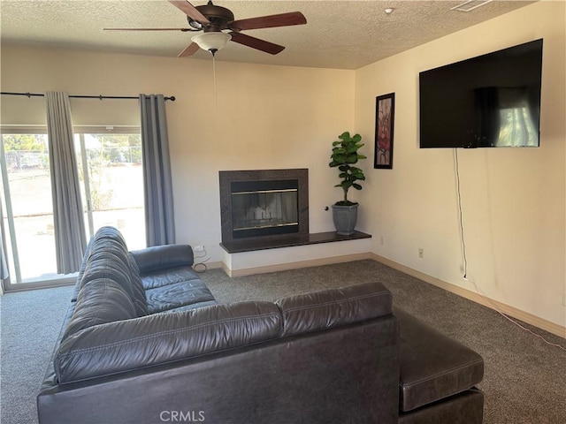 living room featuring ceiling fan, a premium fireplace, carpet, and a textured ceiling