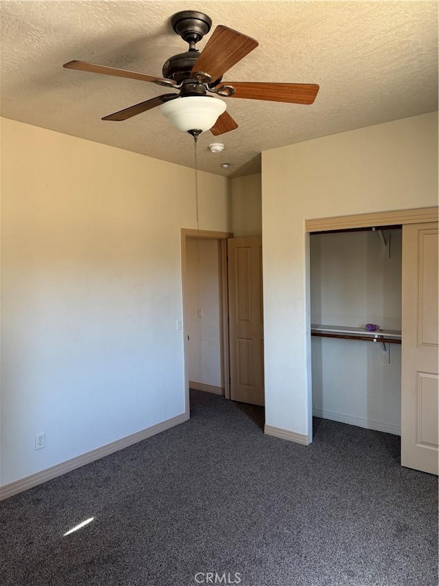 unfurnished bedroom featuring ceiling fan, a closet, a textured ceiling, and dark colored carpet