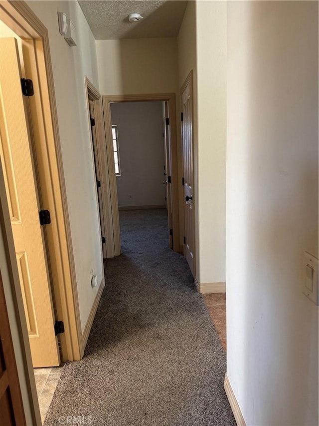 corridor with light colored carpet and a textured ceiling