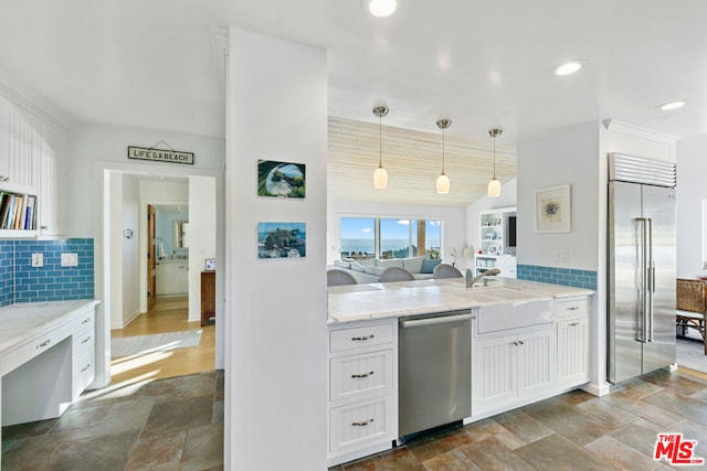 kitchen featuring appliances with stainless steel finishes, decorative light fixtures, white cabinets, decorative backsplash, and light stone counters