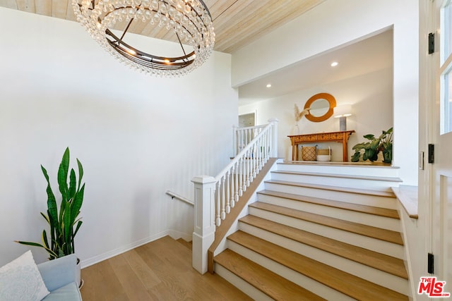 stairs with hardwood / wood-style flooring and an inviting chandelier