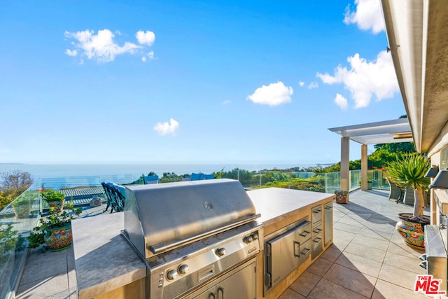 view of patio / terrace featuring area for grilling, an outdoor kitchen, and a water view