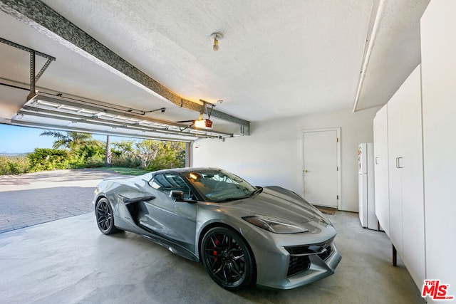 garage with a garage door opener and white fridge