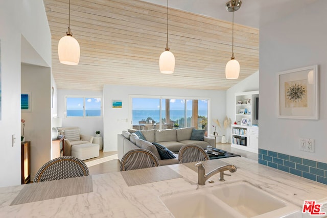 kitchen featuring hanging light fixtures, sink, and light stone counters