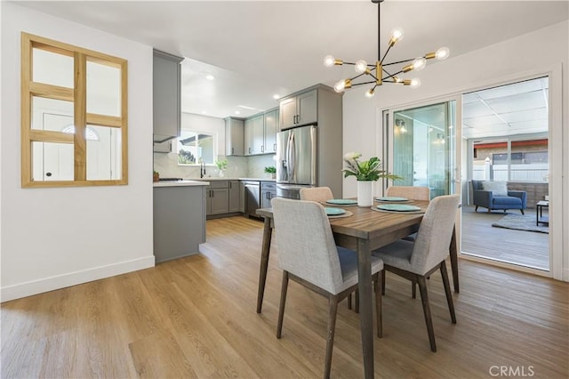 dining room with sink, a notable chandelier, and light hardwood / wood-style floors