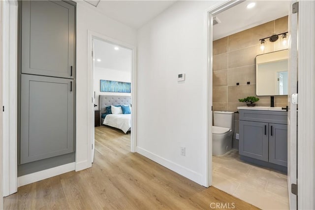 bathroom with vanity, toilet, hardwood / wood-style floors, and tile walls