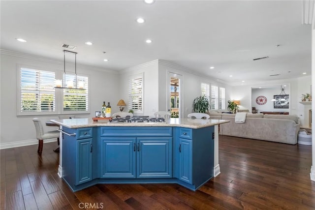 kitchen with blue cabinets, stainless steel gas stovetop, a kitchen island with sink, and hanging light fixtures