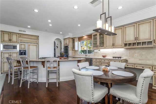 kitchen with pendant lighting, backsplash, dark hardwood / wood-style flooring, a center island, and built in appliances