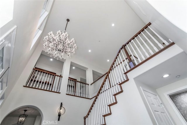 staircase with a towering ceiling and a notable chandelier