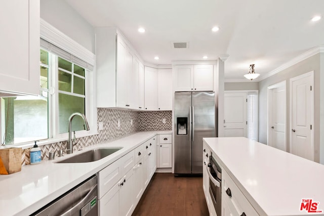 kitchen with sink, backsplash, stainless steel appliances, and white cabinets