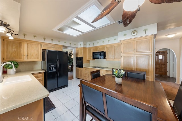 kitchen featuring sink, light tile patterned floors, black appliances, and light brown cabinets