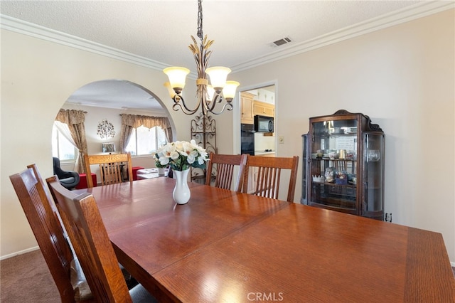 carpeted dining room with crown molding and a chandelier