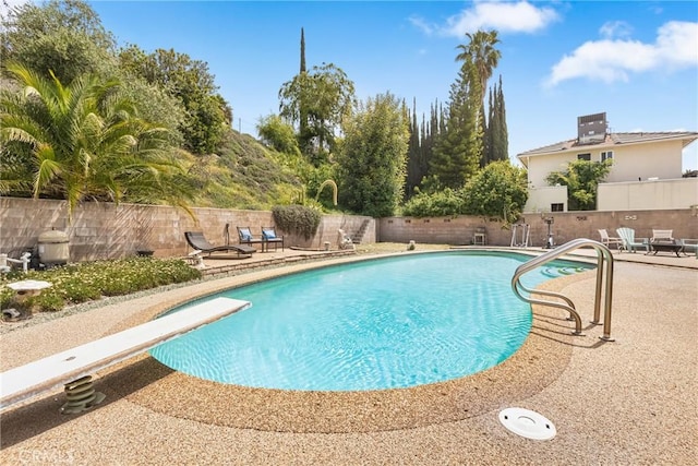 view of pool featuring a fenced backyard, a fenced in pool, a diving board, and a patio area