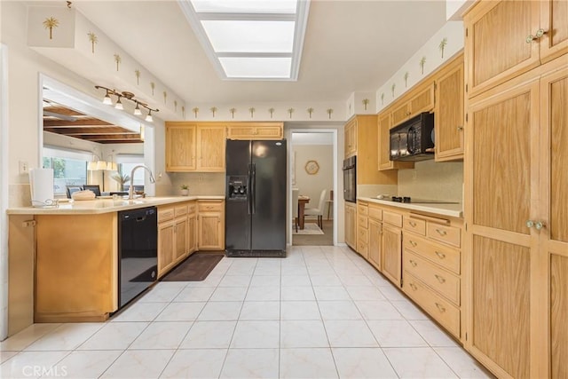 kitchen with light brown cabinetry, light tile patterned flooring, light countertops, a sink, and black appliances