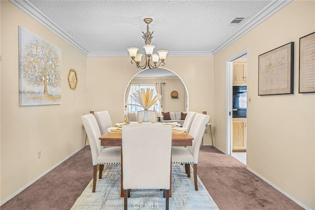 carpeted dining area with an inviting chandelier, ornamental molding, a textured ceiling, and visible vents