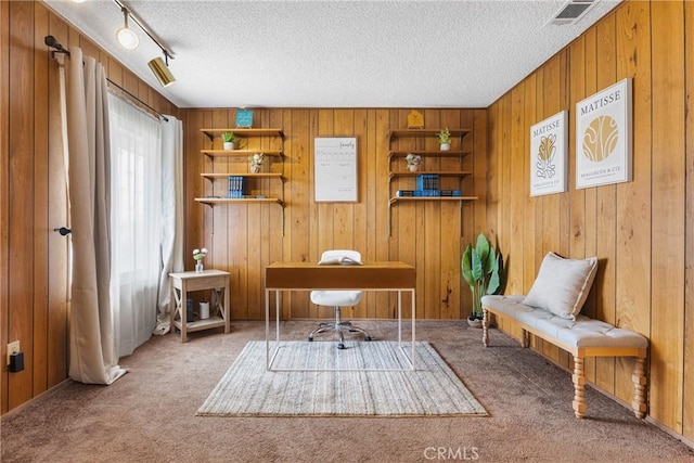 carpeted office with wooden walls, a textured ceiling, and visible vents
