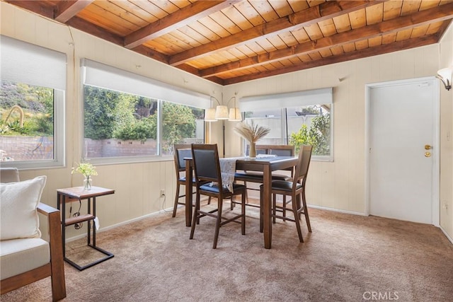 carpeted dining room featuring wood walls, beam ceiling, and wooden ceiling