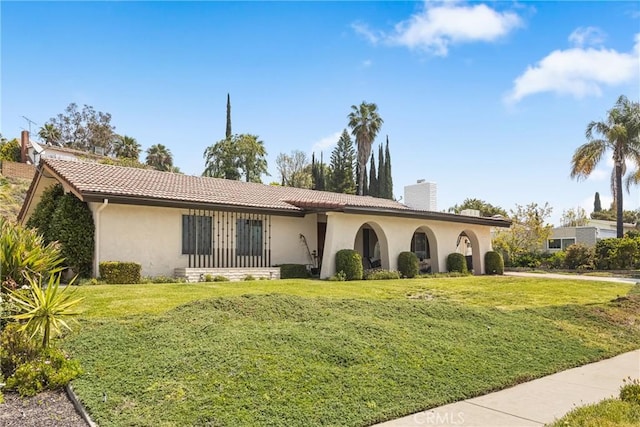 single story home with a tiled roof, a chimney, a front lawn, and stucco siding