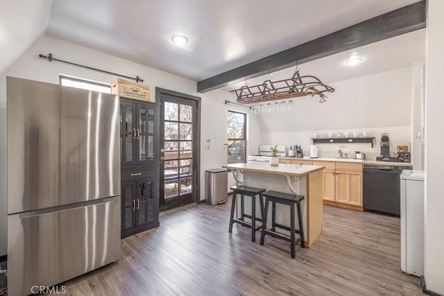 kitchen with a kitchen island, dark hardwood / wood-style floors, dishwasher, stainless steel fridge, and a kitchen breakfast bar