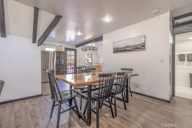 dining space with beamed ceiling and hardwood / wood-style floors