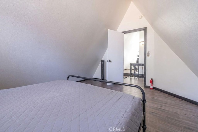 bedroom with vaulted ceiling and hardwood / wood-style floors