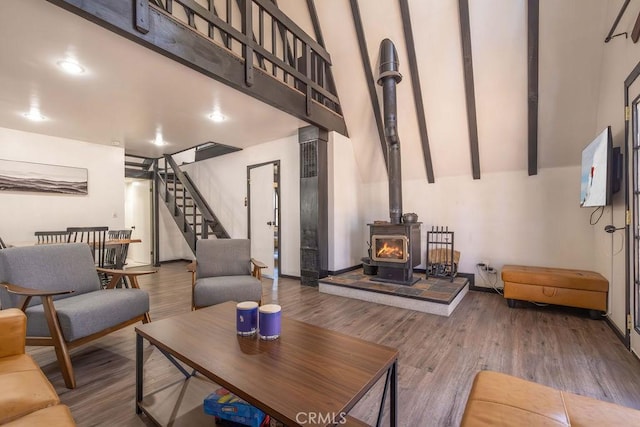 living room featuring beam ceiling, hardwood / wood-style floors, and a wood stove