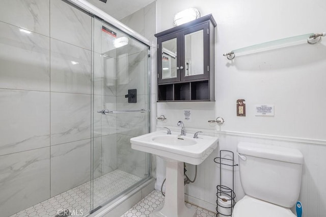 bathroom featuring a shower with door and toilet