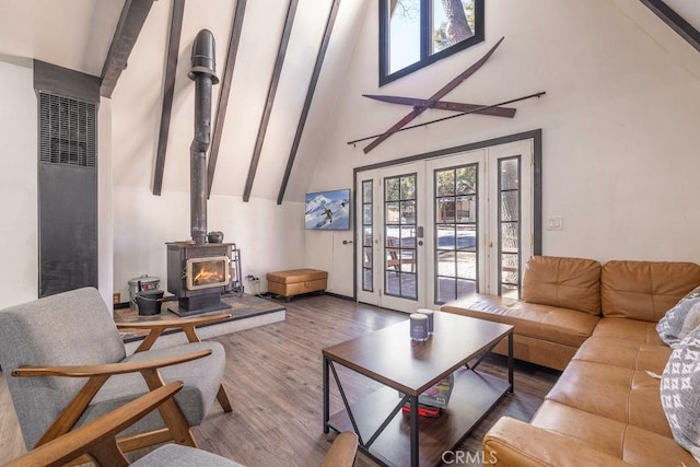 living room featuring hardwood / wood-style flooring, a healthy amount of sunlight, high vaulted ceiling, and a wood stove