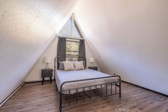 bedroom with lofted ceiling, a textured ceiling, and dark hardwood / wood-style flooring