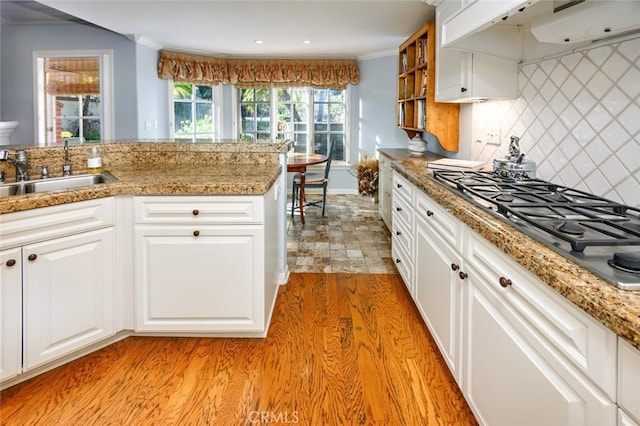 kitchen with sink, light hardwood / wood-style flooring, white cabinetry, ornamental molding, and stainless steel gas cooktop