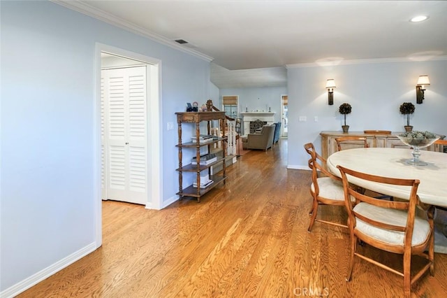 dining space featuring ornamental molding and light hardwood / wood-style floors