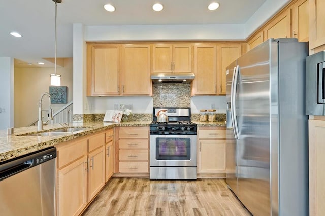 kitchen with sink, hanging light fixtures, light brown cabinets, appliances with stainless steel finishes, and light hardwood / wood-style floors