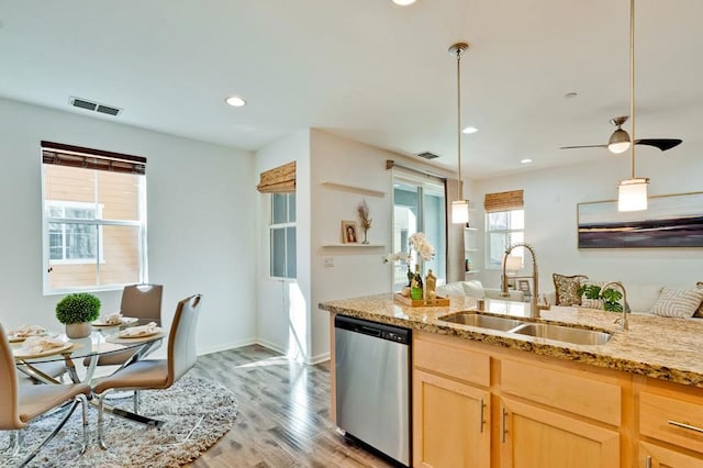 kitchen featuring light brown cabinetry, sink, hanging light fixtures, stainless steel dishwasher, and light hardwood / wood-style floors