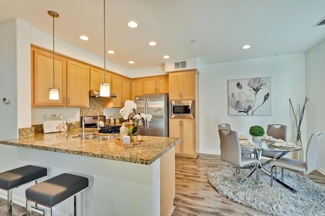 kitchen featuring stainless steel appliances, sink, kitchen peninsula, and decorative light fixtures