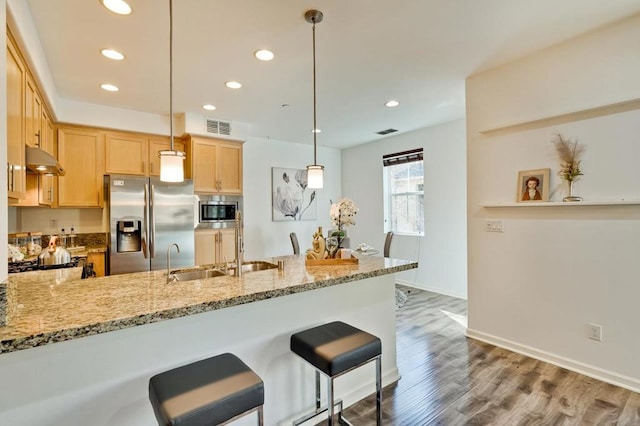 kitchen featuring light brown cabinetry, sink, appliances with stainless steel finishes, kitchen peninsula, and pendant lighting