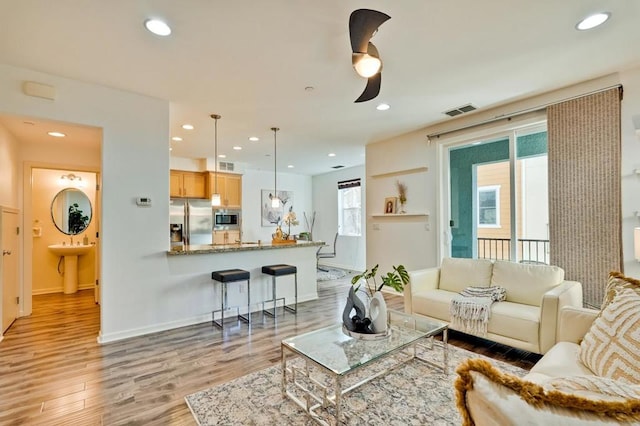 living room featuring ceiling fan, a wealth of natural light, and light hardwood / wood-style floors