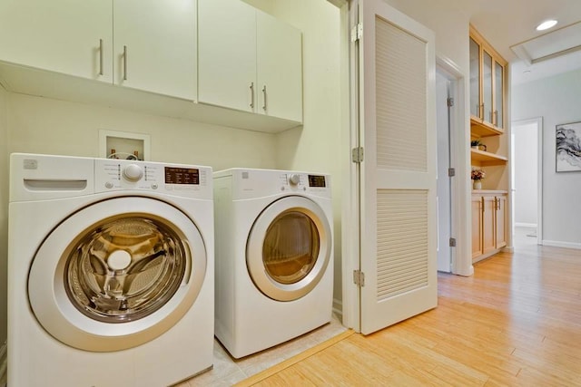 washroom with cabinets, light wood-type flooring, and washing machine and clothes dryer