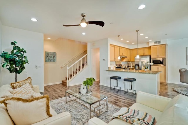 living room featuring sink, light hardwood / wood-style floors, and ceiling fan