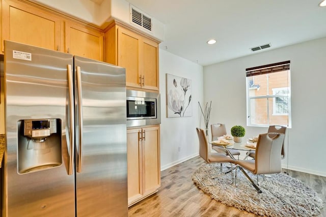 kitchen featuring light stone countertops, light brown cabinets, light hardwood / wood-style floors, and appliances with stainless steel finishes