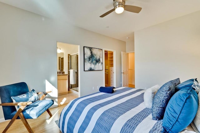 bedroom featuring ceiling fan, a spacious closet, light hardwood / wood-style floors, and ensuite bath